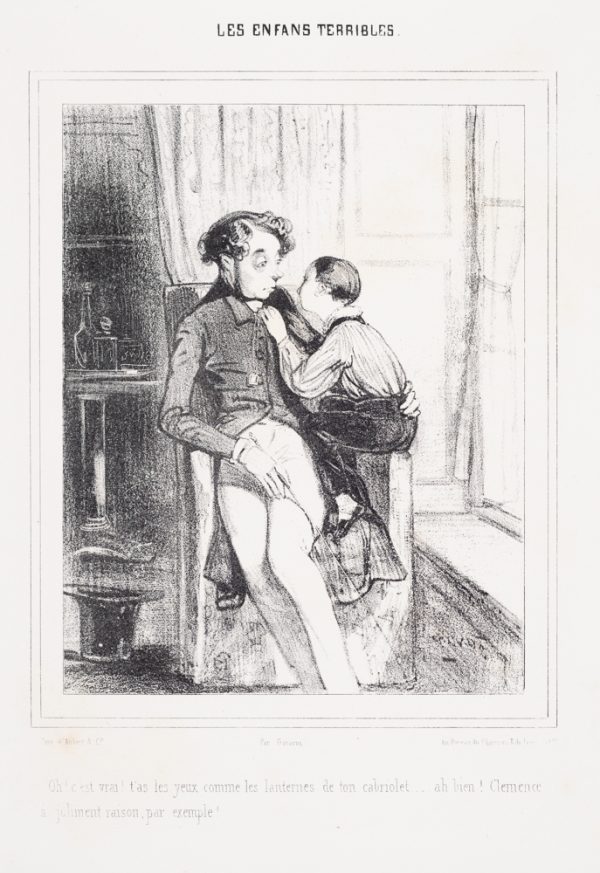 A young boy crouches on an arm of a chair talking to a man seated there.