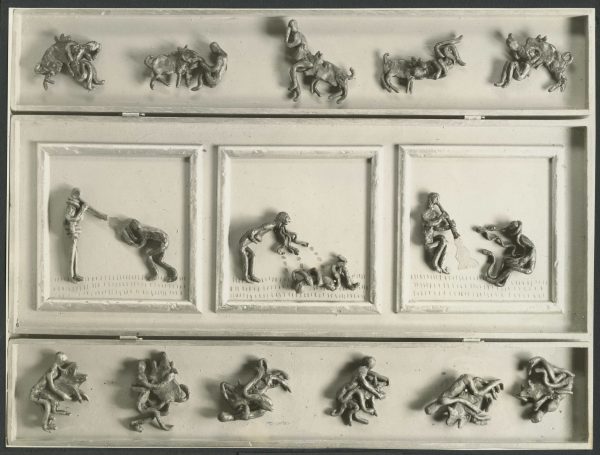 17 cast lead figures on an orange and gold background. The figures are grouped with animals and the center three have some additional gold background.