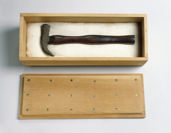 Iron claw hammer with rosewood handle, resting on padded suede leather, in pine box with lid.
