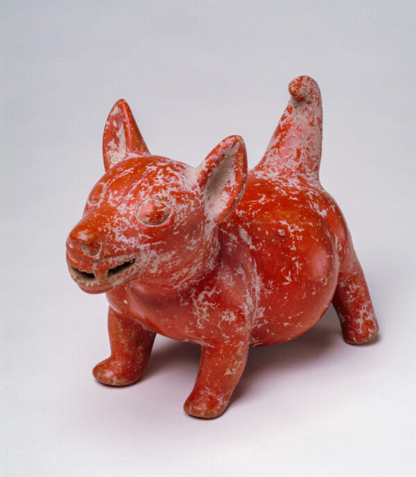In red polished clay a fat dog with large ears and a smiling mouth.