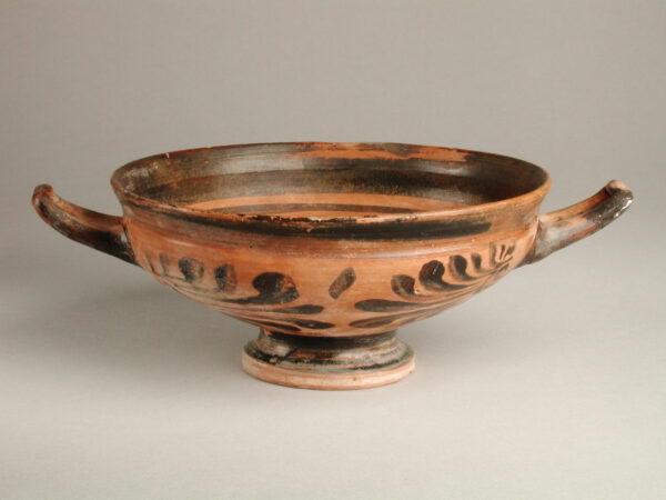 Shallow bowl with foot and two handles, red body with black decoration.