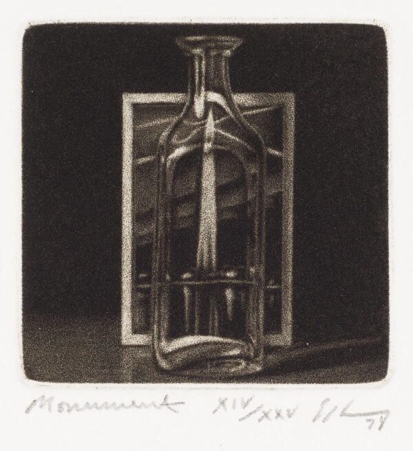 A clear bottle with square sides. A postcard of a tower can be seen through the glass.