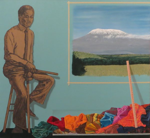 A man is seated on bar stool at left. A painting of a snow-capped volcano, bordered by strips of masking tape at upper right. There is a pile of textile scraps along the bottom of composition, with yardstick at lower right.