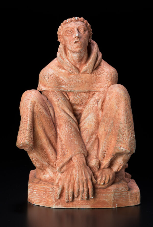 A maquette of a larger statue of St. Francis, crouched and looking up.