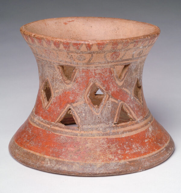 A pot stand: tan body, red and dark brown slip with triangular shaped pierced sides.