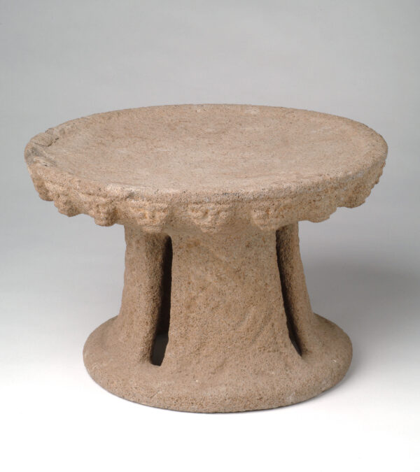 A round flat metate with tall stand.