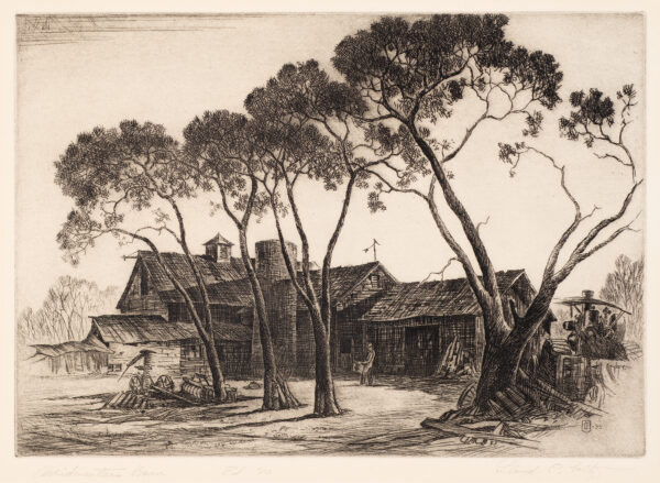 Man stands drawfed by barns and trees in front.