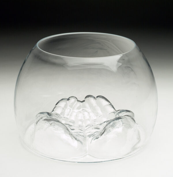 A glass container with shape of cupped hands pressing the glass up from the bottom.