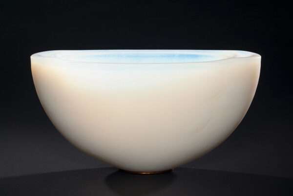 An elongated bowl shape that is thicker at the sides than in the middle. The interior is textured soft wave patterns and the exterior has a finer rough surface. The top is polished smooth. The exterior color is from bottom up: gray, yellow, blue. The interior is a faint blue-green. The foot is copper clad with felt spots.