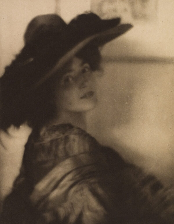 ¾ Portrait of a woman wearing a hat. She is looking over her right shoulder.