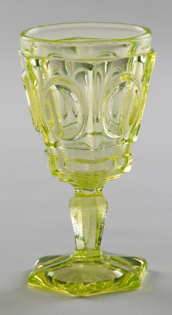 Clear-vaseline colored goblet with ringed frame ovals and hex base.