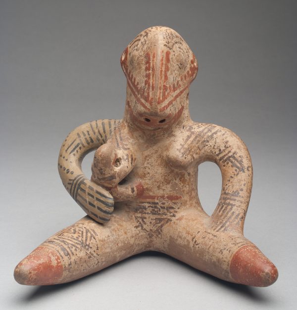 Buff clay body with red ochre and black slip decoration. It is of a mother sitting with legs outstretched with a baby at her breast.