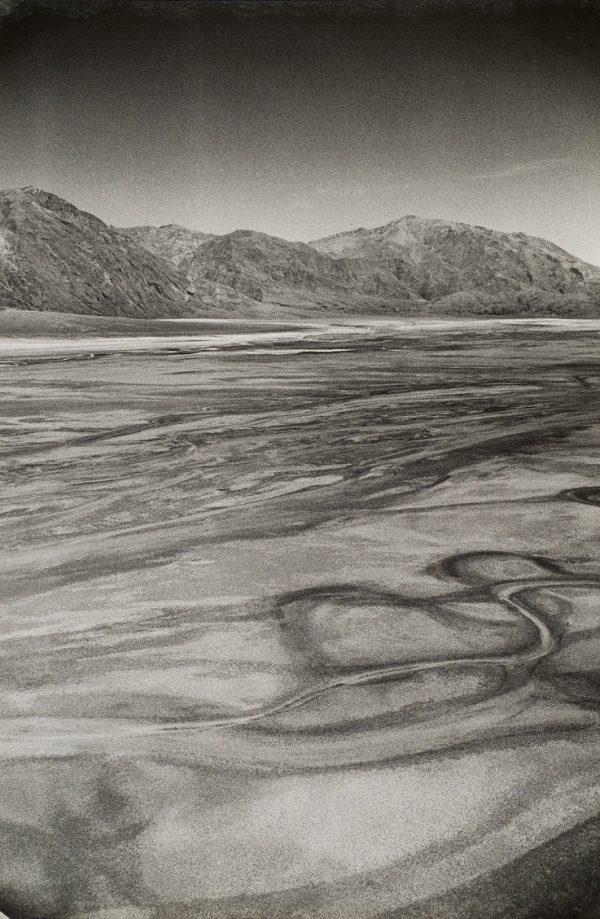 Patterns in desert with mountains in background.