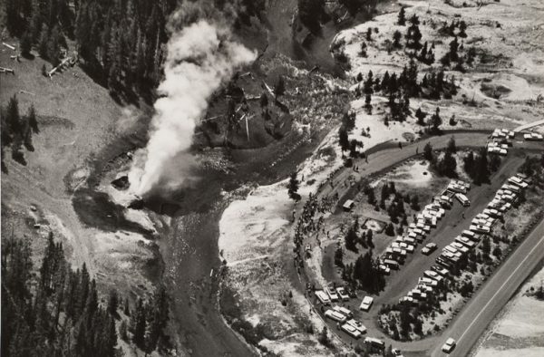 View of Yellowstone geyser on left and parking lot on right.