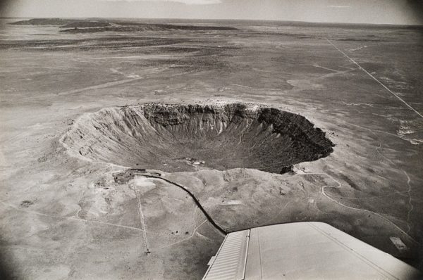 A meteor crater in the desert. The wing of the plane is at lower right.