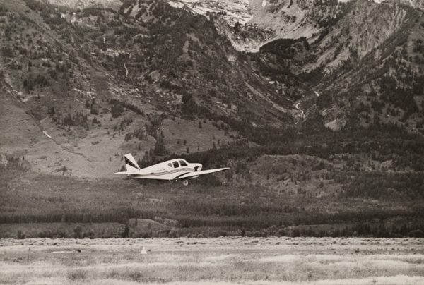 A small plane is taking off with mountain in background.
