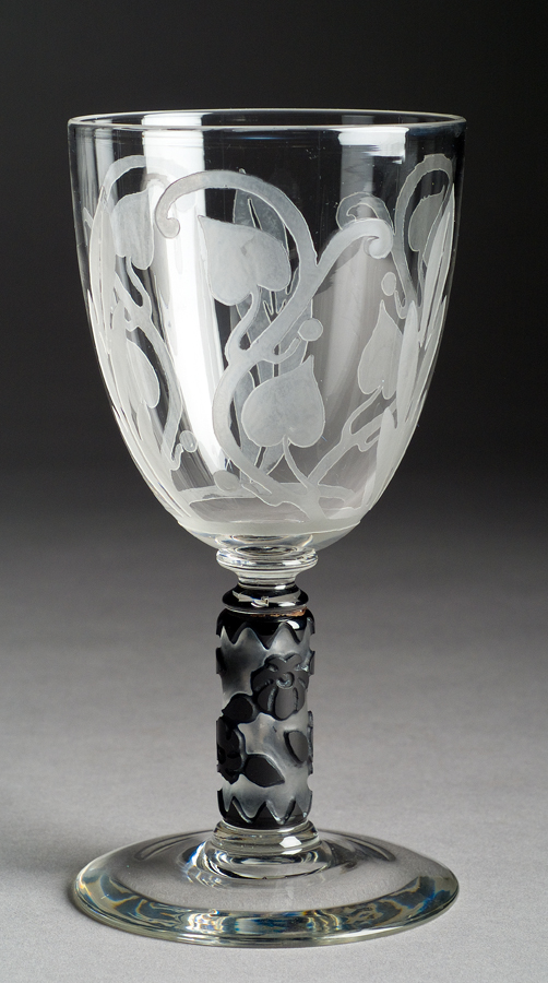 A clear goblet with the bowl etched with foliage design and black flowers on stem.
