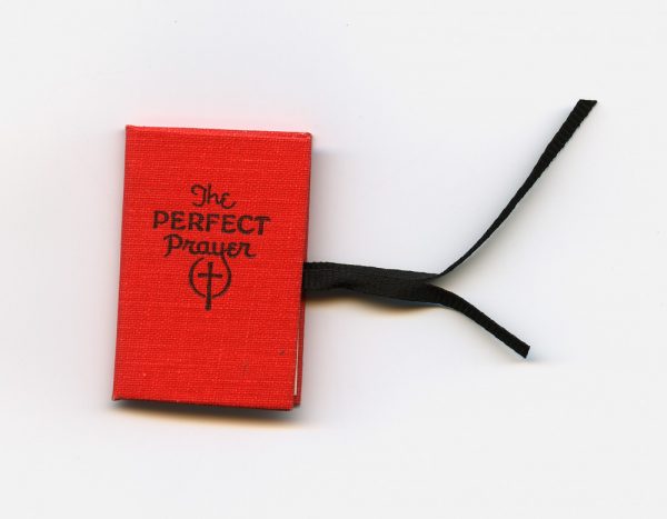 A hard-bound book with red cover and white accordion fold pages. (They are loose at one end.) Printed in purple ink. The text is also known as the Lord’s Prayer, Matthew 6: 9-13. The book has black ribbon ties.