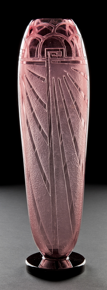 A tall amethyst colored vase in Art Deco style engraved with radiating lines and arches.
