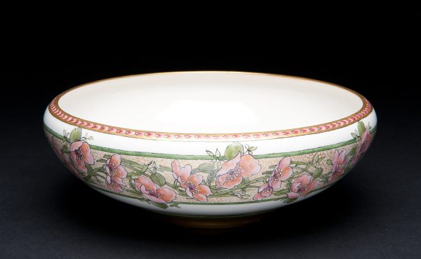 A shallow bowl with pink flowers and green foliage in 2 1/4” band around outside at top and on inside bottom.