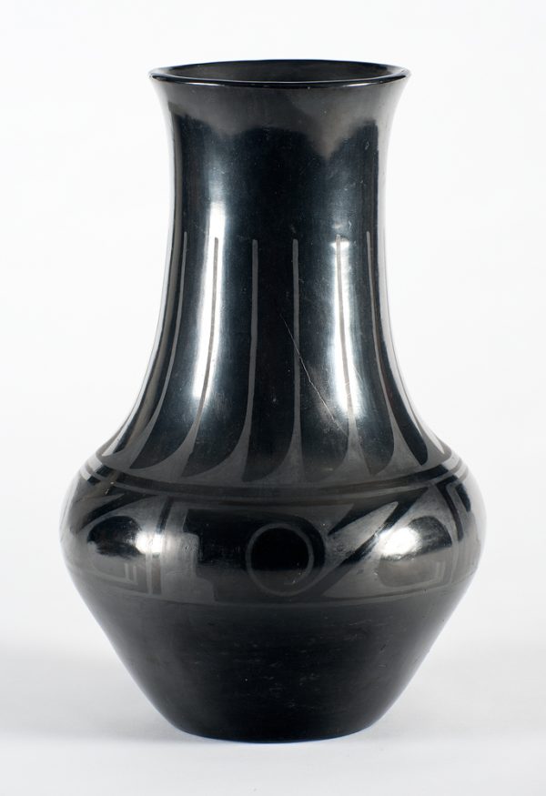A black-on-black pot decorated with a feather pattern in the upper half and a varied abstract pattern around the belly.
