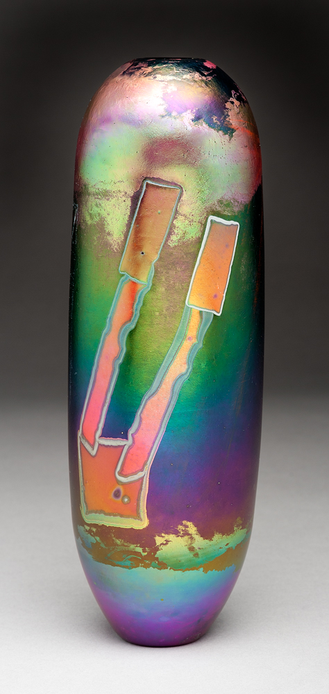A black column vase with narrow inverted base and rounded shoulders toward a narrow mouth opening. The surface decoration is red/orange and gold iridescent geometric shapes on a green gradient to purple background with gold over purple at top and bottom.