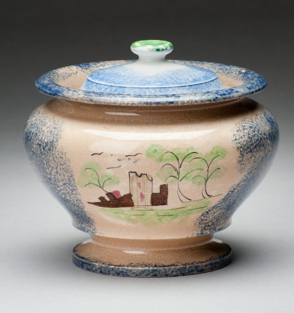 Spatterware sugar bowl in the Fort pattern, blue with scene of buildings. The opposite side of the bowl has a scene of grass, tree and fence.