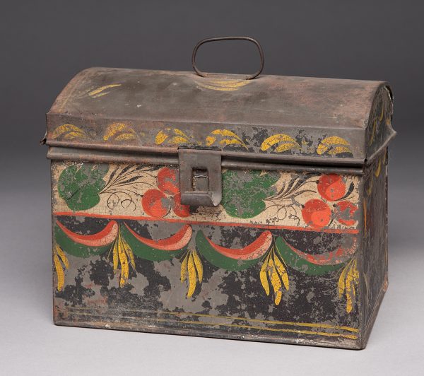 A tole painted metal bin. The decoration is around the edges and on the front vertical side. The top row has two groups of three fruit and green leaves. The bottom is orange, pink and green swags (watermelon?) with groups of three yellow brushstrokes between.