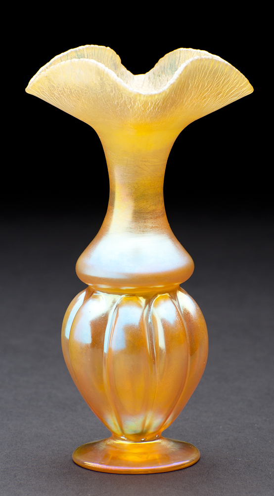 shape #134, The lower 1/3 is footed and segmented in highly reflective surface. The upper part starts wide at the center and moving up, narrows before opening to a wide lip that folds back on itself on four sides. The outside of the upper part is mat and the flaring lip has an alligator surface.