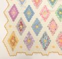 Cotton top, back and batting is hand stitched with multicolored six-sided pieces. The edge shape follows the diamond field pattern and has a yellow/gold binding. The stitches average 7-9 stitches to the inch.
