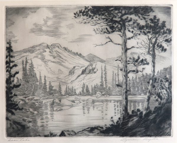 A lake with mountains in the background, trees line the shore with large rocks scattered in the lake. Two large pines are at the right.