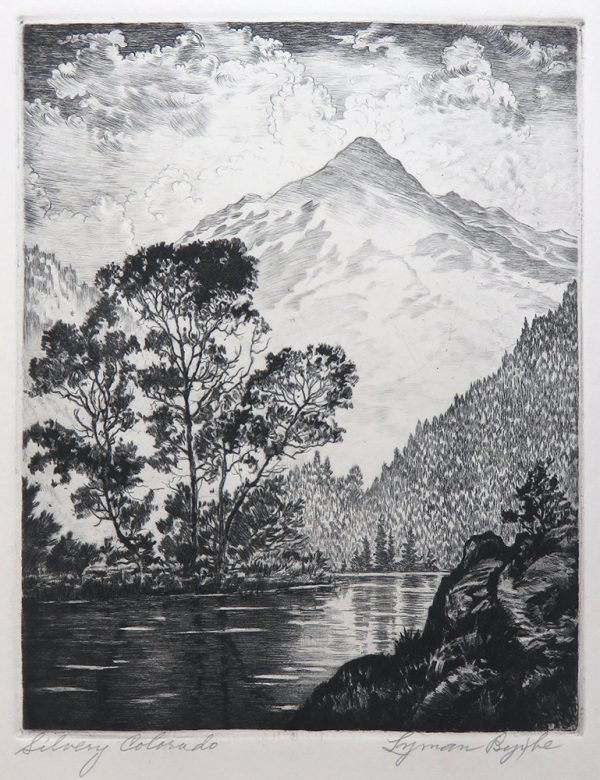 A very tall mountain peak is in the background. In the foreground is a lake with ricks on the right and trees on the far shore, reflected in the water. The sky is dark with an abundance of white clouds.