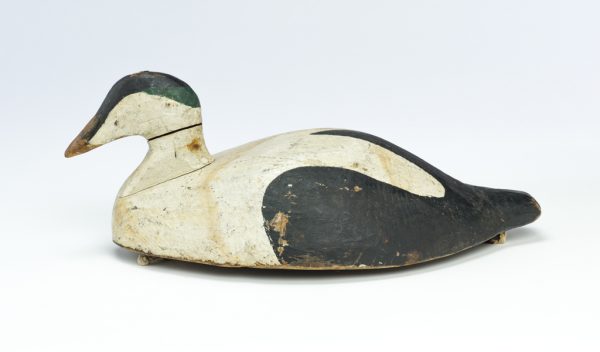 A carved and painted wood decoy. It is white with black near the tail and on creast of head