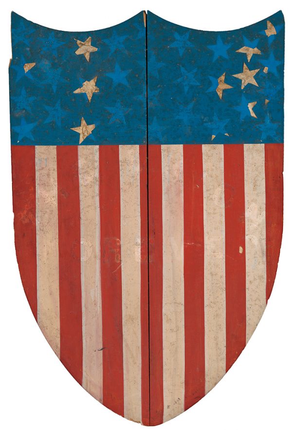 A large painted wood shield. The top is painted blue with 30 applied white paper stars. The bottom is painted with red and white vertical stripes. There is a shadow of text on the stripes that appears to have read “The Union Forever”.