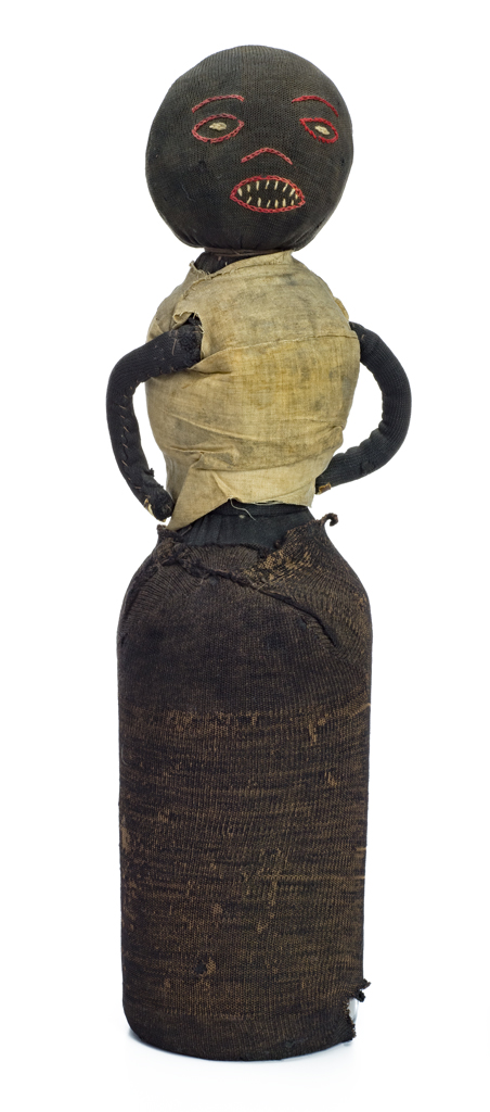 A freestanding bottle doll with stitched face. The doll would have been originally dressed in additional clothes. All that remains present is a white undershirt. A glass bottle filled with dirt or sand forms the structure of the doll, which is covered with black stockinette. Two curved arms are attached to the body.