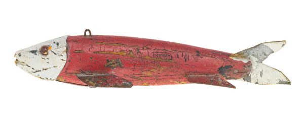 A carved and painted wood fishing lure. The body is red with a white head and tail, amber eyes.