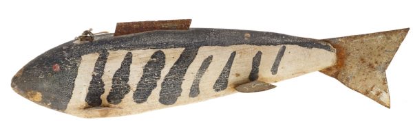 A carved and painted fishing lure. The body is made of wood, while the 5 fins and tail are made of cut sheet metal. A lead weight is embedded in the underside of the body. The fish is painted overall with black and white stripes.