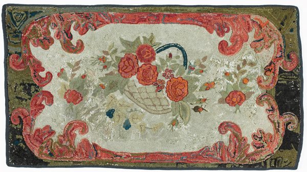 A hooked rug with a basked of red roses on a white ground. The hooked border includes the same red on a brown and black edge.