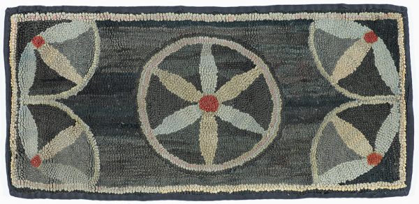 a hooked rug with, at center, a full six-point star in white with red center on dark gray background.  The corners have half stars.