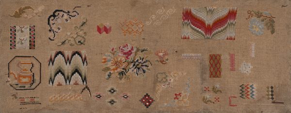 A variety of patterns are scattered throughout the sampler. At center left is a teapot, at center and top right are flowers, at left and top right is a flame design.