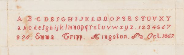 Embroidered red alphabets on white linen. There are Upper and lower case letters, plus numbers.