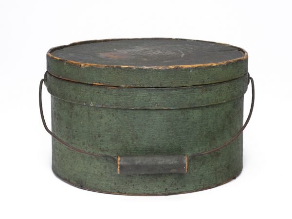 A round lidded box with wire and wood handle in green paint.