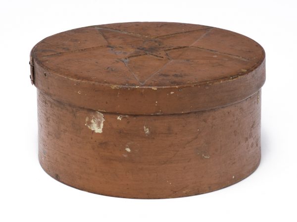 A brown round box with a star on the lid. The interior of the lid has a sketch for a round triangular chip carving, including penciled math. Possibly from Maine.