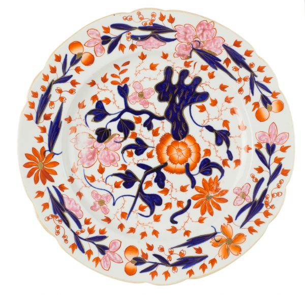 A glazed ceramic dinner plate with floral design in red orange, pink, blue, and gold.