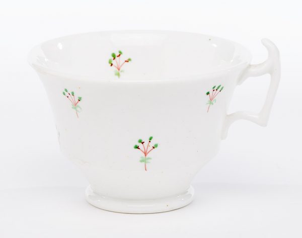 A small ceramic saucer with clear speckled high-gloss glaze and sprig pattern overglaze. The ceramic body is white and translucent, likely porcelain.