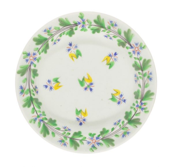 A dish with decorations around the rim of green folage and six yellow and green floral motifs are at the center.