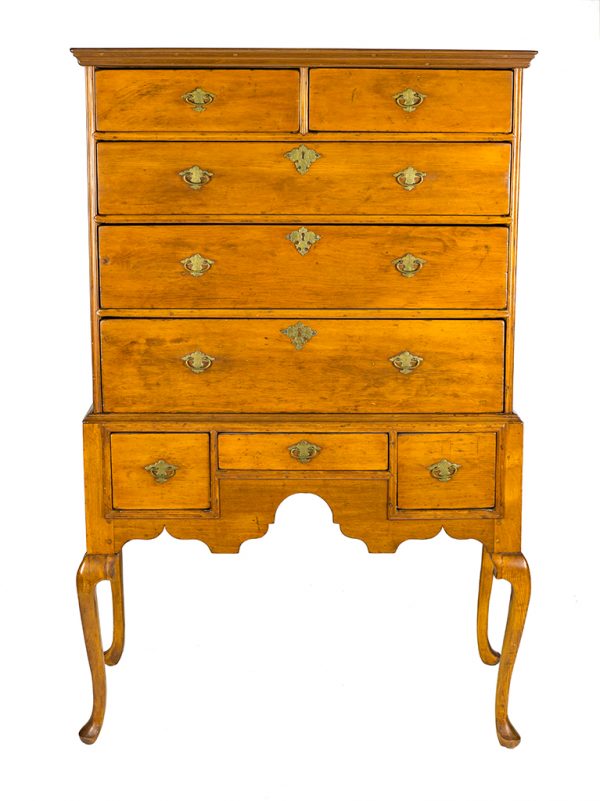 A Queen Anne style highboy that has a double arch at the apron, two drawers over three over three, and elongated feet.