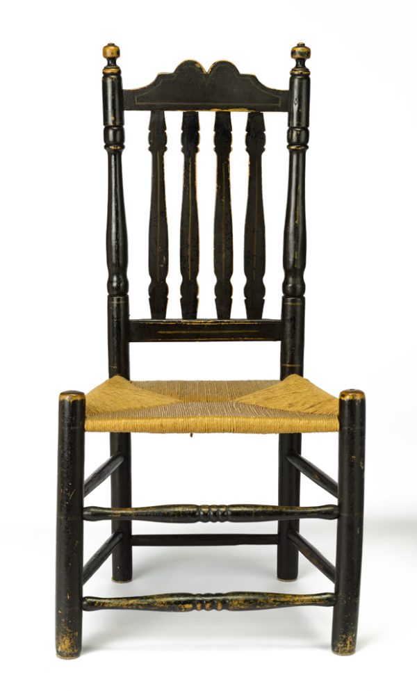 A banister side chair with turned stiles and legs, seven turned stretchers, and a woven rush trapezoidal seat.
The wooden structure is painted overall with black paint.