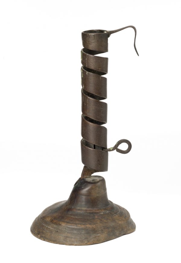 A candlestick holder of cut and twisted metal with pushup to raise or lower the candle, the base is turned wood