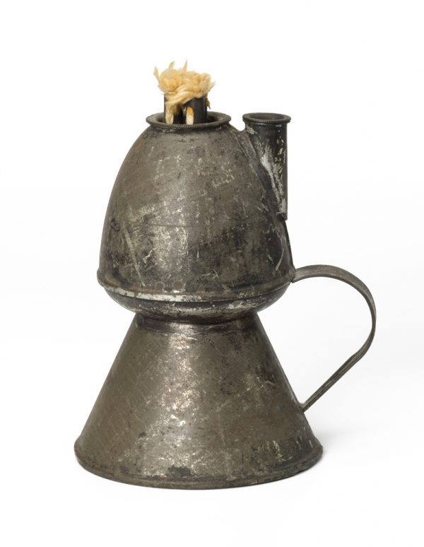 A lamp made of copper and tin. The shape is two levels, a funnel shape of the bottom and a bulbous shape on top, with a lidded spout to fill with oil and three wicks. Strap handles.
